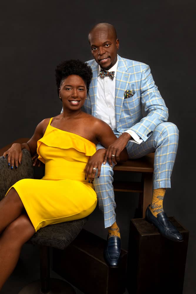 Branding photo of a stylish, pretty black woman in yellow dress sitting with stylish handsome black man in sky blue suit. Charles and Tiffane Davis of A Polished Man Personal Branding photo session.