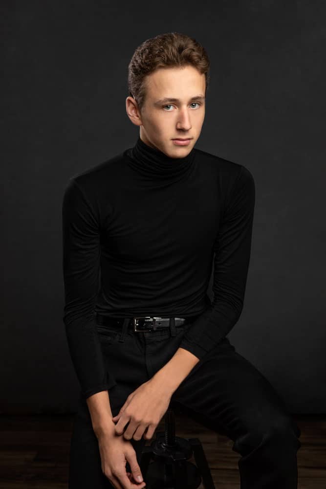 Sharp photo of a handsome high school senior with a black turtleneck shirt, black jeans and black belt. Elmore Senior Portrait Photography.
