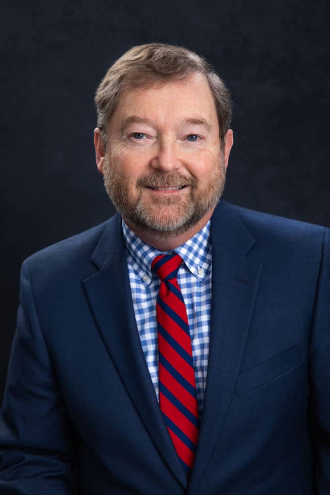 Branding photo of a sharply dressed, smiling man with blue suit and red striped tie. Financial Advisor. Brian Thomas Headshot Photography.